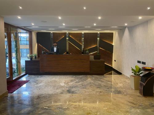 a man sitting at a desk in a lobby at Royal Ace Boutique Hotel - Manyata Techpark in Bengaluru