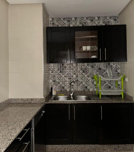 a kitchen with black cabinets and a sink at Nice Apartment in Marina Agadir in Agadir