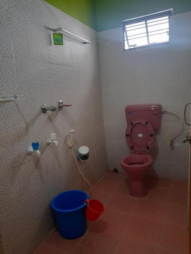 uma casa de banho com um WC cor-de-rosa e um balde azul em Shanti Kunj Homestay em Agartala