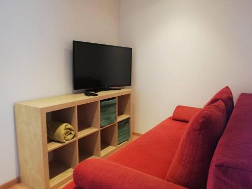 Urlaub in Alberschwende في البيرشوينده: غرفة معيشة مع أريكة حمراء وتلفزيون بشاشة مسطحة