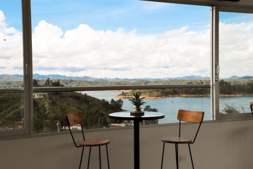 a room with a table and chairs and a view of a river at Hotel Santorini in Guatapé