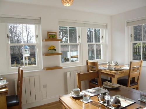 ein Esszimmer mit einem Tisch, Stühlen und Fenstern in der Unterkunft Ivy Cottage Bed and Breakfast in Braemar