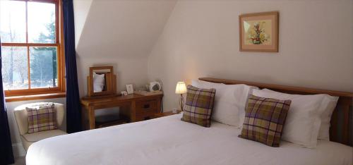 1 dormitorio con cama blanca y ventana en Ivy Cottage Bed and Breakfast en Braemar