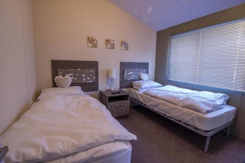 2 camas individuales en una habitación con ventana en Stunning 4 Berth Lodge With Decking At Manor Park In Hunstanton Ref 23173k en Hunstanton
