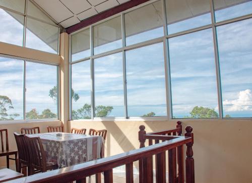a room with a table and chairs and windows at Hillcrest Haputale in Haputale