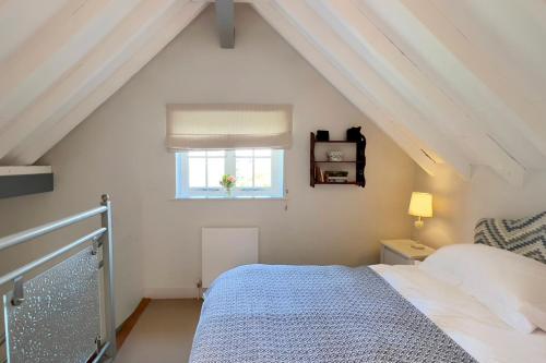 a white bedroom with a bed and a window at The Buttery in Freston