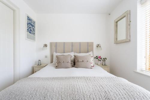 a white bedroom with a large white bed with pillows at 1 Garden Apartment in Kingsbridge