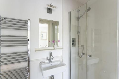 a white bathroom with a sink and a shower at 1 Garden Apartment in Kingsbridge