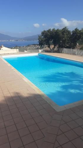 une grande piscine bleue avec l'océan en arrière-plan dans l'établissement Charmant studio, à Grosseto-Prugna
