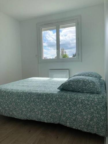 een witte slaapkamer met een bed en een raam bij Maison indépendante avec jardin in Le Mans