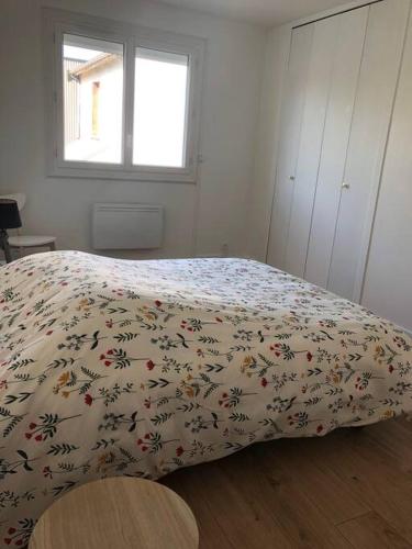 een slaapkamer met een bed met een deken met bloemen erop bij Maison indépendante avec jardin in Le Mans