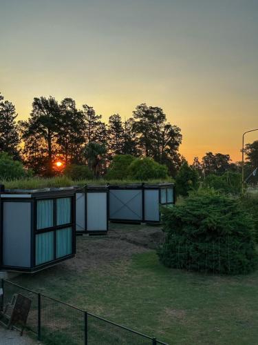 Ein Haus auf einem Feld mit dem Sonnenuntergang im Hintergrund in der Unterkunft Greenboxaparts in Firmat