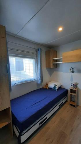 une chambre avec un lit dans une pièce avec une fenêtre dans l'établissement Mobil-home Loic camping les Dunes de Contis, à Saint-Julien-en-Born