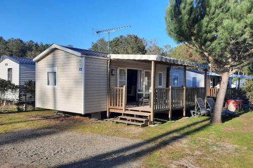 a tiny house with a porch and a deck at Mobil-home Loic camping les Dunes de Contis in Saint-Julien-en-Born