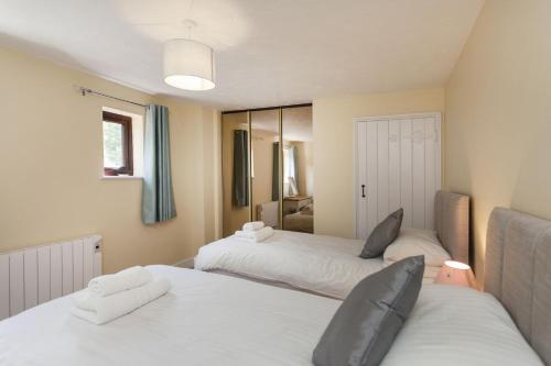 a bedroom with two white beds and a mirror at Burnham B in Blakeney