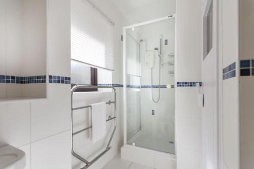 a white bathroom with a shower and a sink at The Kelling in Blakeney