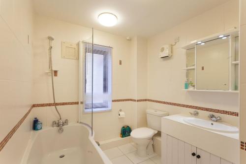 a bathroom with a tub and a toilet and a sink at Burnham A in Blakeney