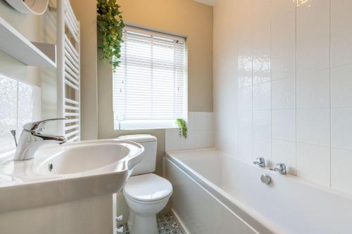 een badkamer met een toilet, een wastafel en een bad bij Corner Cottage in Norwich