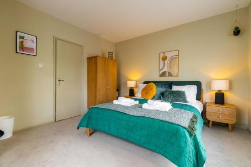een slaapkamer met een groen bed met 2 handdoeken erop bij Corner Cottage in Norwich