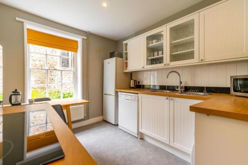 a kitchen with white cabinets and a sink at Princes Cottage in Norwich