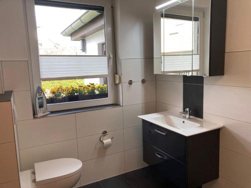 ein Bad mit einem WC, einem Waschbecken und einem Fenster in der Unterkunft Ferienwohnung OstseeStrandLäufer 3 in Zingst