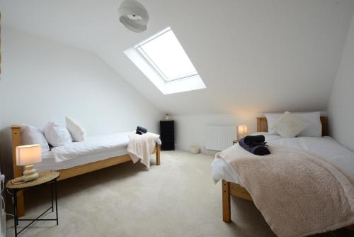 a bedroom with two beds and a skylight at Rollestone New Forest (HOT TUB) in Salisbury