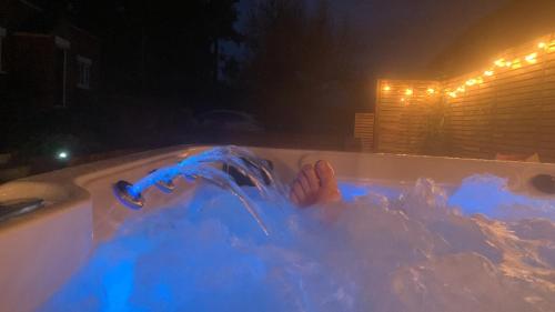 a person laying in a bath tub at night at Fantastic Location, Annexe with Hot Tub in Warmingham