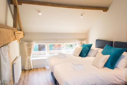 two beds in a room with two windows at Boathouse Barn in Coltishall
