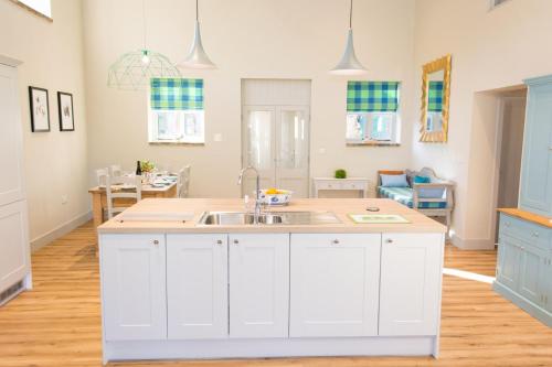a kitchen with white cabinets and a sink at Boathouse Barn in Coltishall