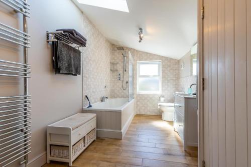 y baño con bañera, aseo y lavamanos. en St Josephs Cottage, en West Runton