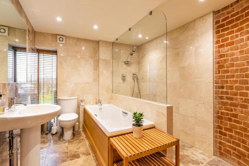 a bathroom with a tub and a toilet and a sink at Owl Barn in Sculthorpe