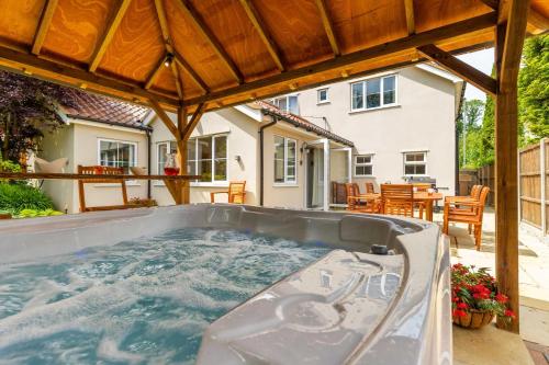 a hot tub on a patio with a house at Woodside House in Costessey