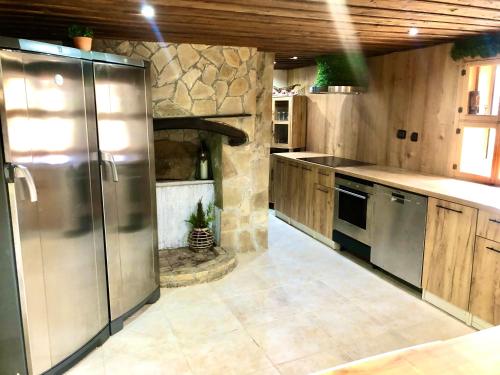 a kitchen with a refrigerator and a stone oven at Попската къща-възрожденски дух и съвременни удобства in Medven