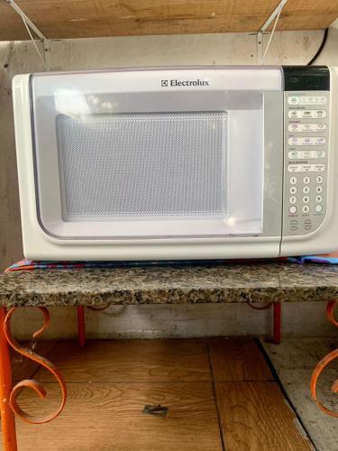 a white microwave sitting on top of a table at Suite familiar completa in Búzios