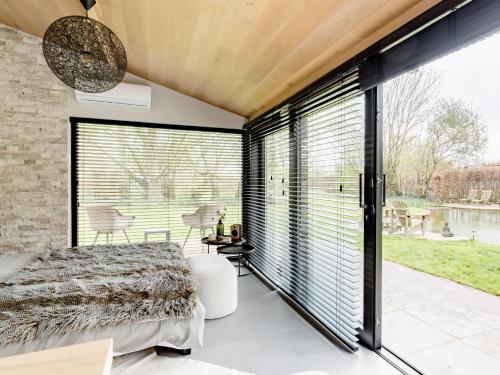 Schlafzimmer mit großen Fenstern, einem Bett und Blick auf das Wasser in der Unterkunft Bulsomhuys in Kampenhout
