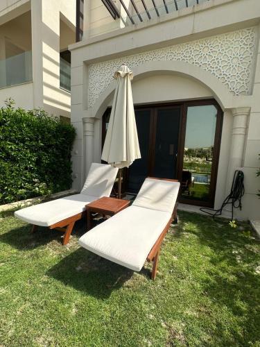 two lounge chairs and an umbrella on the grass at Hawana Salalah luxury 1BR TH with private pool in Ma‘mūrah