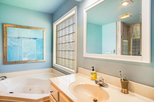 a bathroom with a sink and a tub and a mirror at Plantations East - 221 Lakeside Dr in Lewes