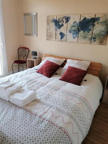 une chambre avec un grand lit avec des oreillers rouges dans l'établissement Le p'tit appart, à Sarlat-la-Canéda