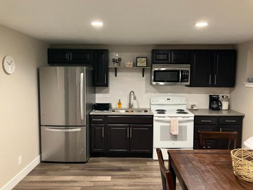 a kitchen with black cabinets and a stainless steel refrigerator at Cozy Getaway near SLC Airport & Downtown - 1st floor Apartment in Salt Lake City