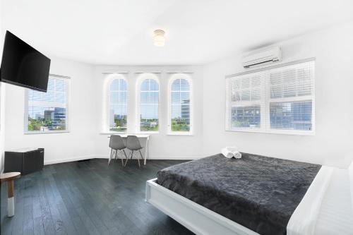 a white bedroom with a bed and windows at The Variety by LuxUrban in Miami Beach