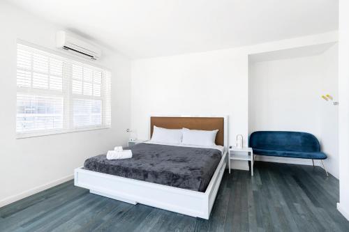a white bedroom with a bed and a blue chair at The Variety by LuxUrban in Miami Beach
