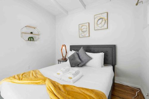 a bedroom with a white bed with a yellow blanket on it at Mid Century Garden View Home Parking in San Mateo