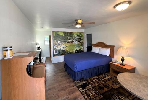 ein Hotelzimmer mit einem Bett mit blauer Tagesdecke in der Unterkunft Myrtle Lane Inn in Coquille