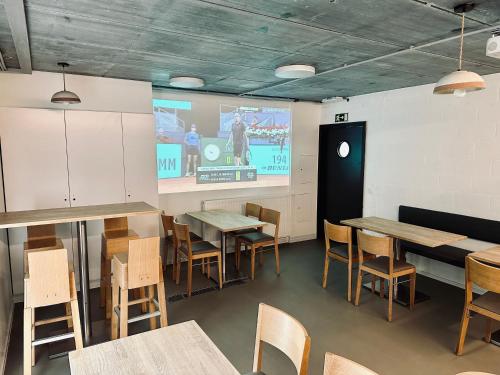 a dining room with tables and chairs and a screen at La Bel échappée in Aubel