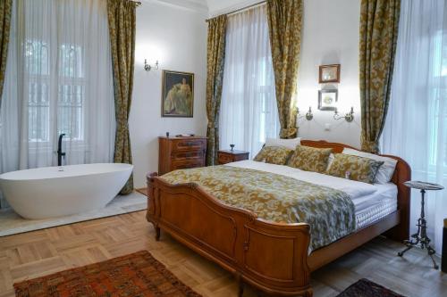 a bedroom with a large bed and a bath tub at Prónay-kastély in Alsópetény