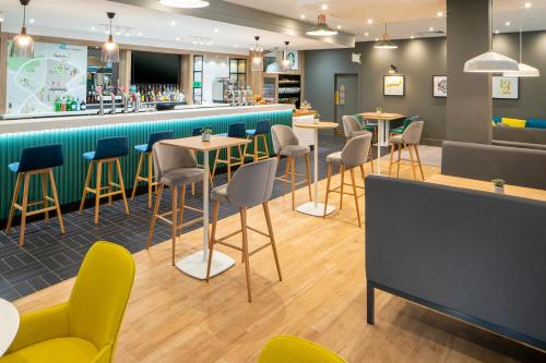 a restaurant with tables and chairs and a bar at Holiday Inn Aylesbury by IHG in Aylesbury