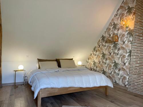 um quarto com uma cama grande e lençóis brancos em Le gîte du four à pain em Noyers-sur-Cher