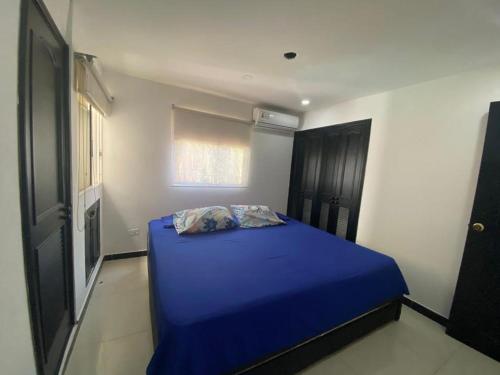 a blue bed in a room with a window at Apartamento a 2 cuadras de la playa Rodadero in Rodadero