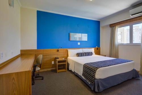 - une chambre avec un lit et un mur bleu dans l'établissement Quality Hotel Jundiaí, à Jundiaí