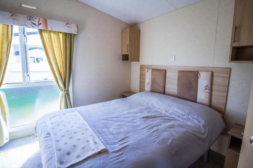 a bedroom with a bed and a large window at Lovely 6 Berth Caravan Nearby Hunstanton Beach In Norfolk Ref 23071t in Hunstanton
